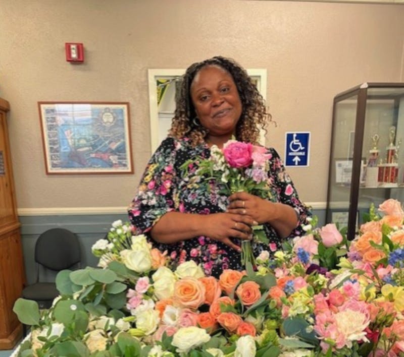 Person holding a small bouquet of flowers, standing in front of many flowers