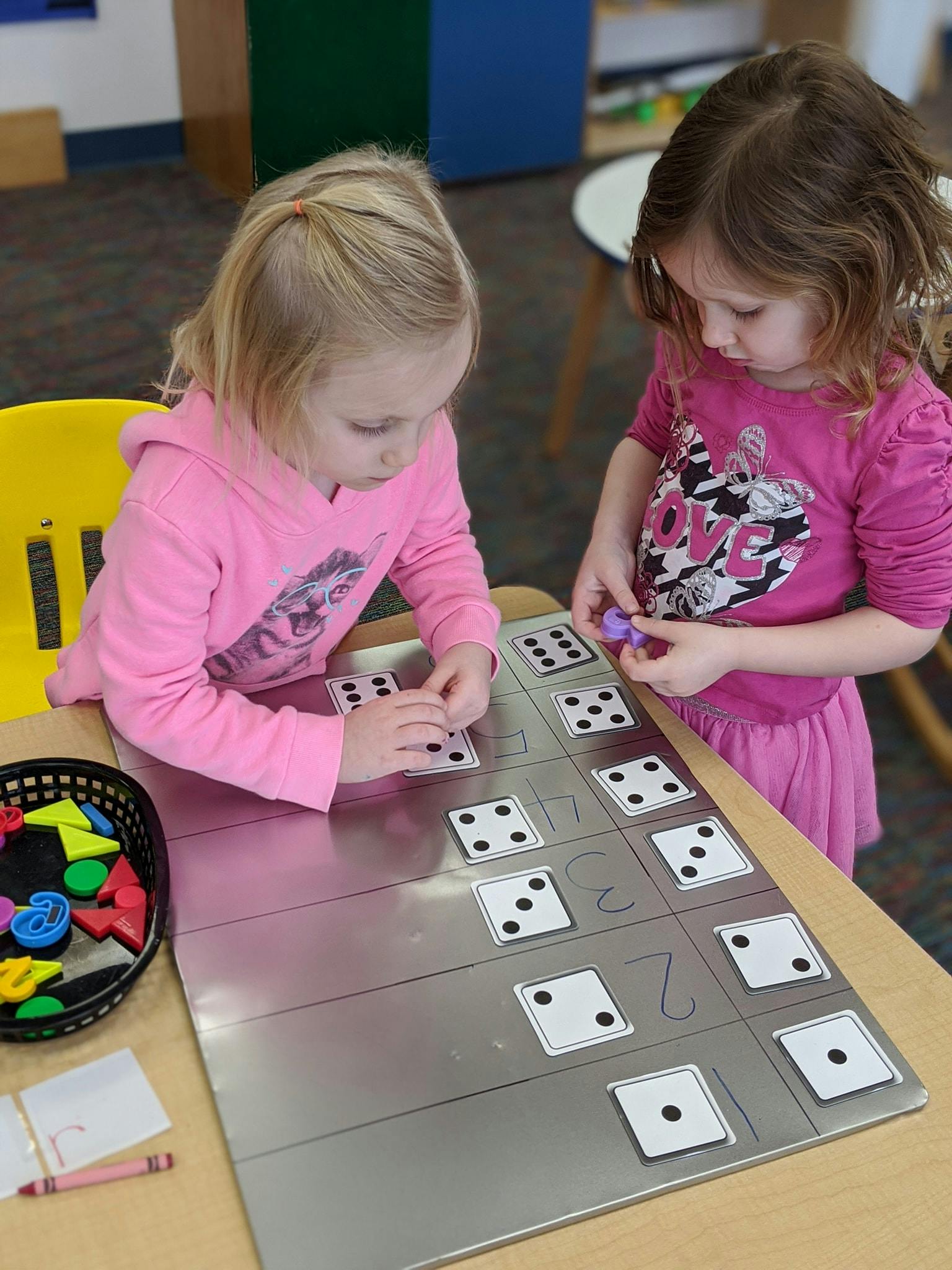 Two children playing with dice cards on a table