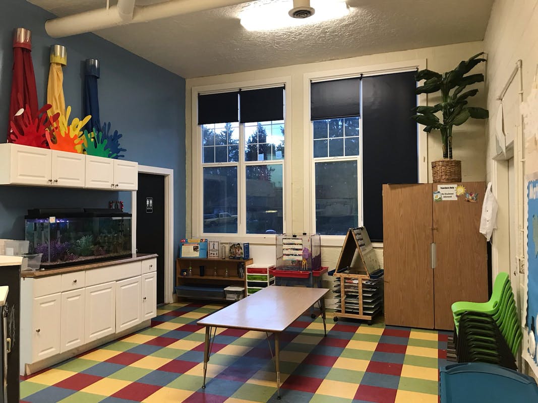 Classroom with colorful checkered floor, windows, and a long table