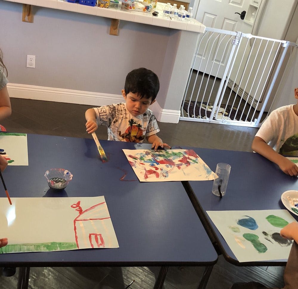 Child painting at a table with other children