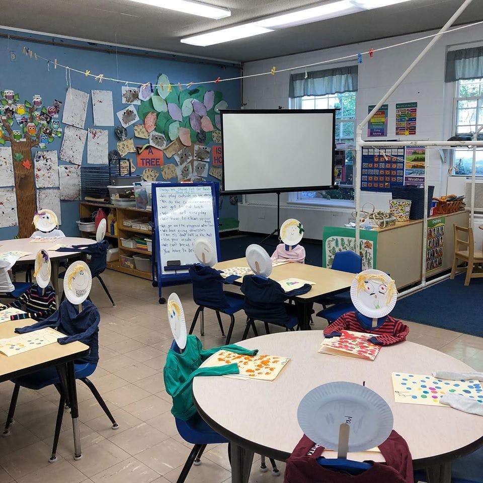 Classroom with tables and chairs, paper plate figures sitting at desks