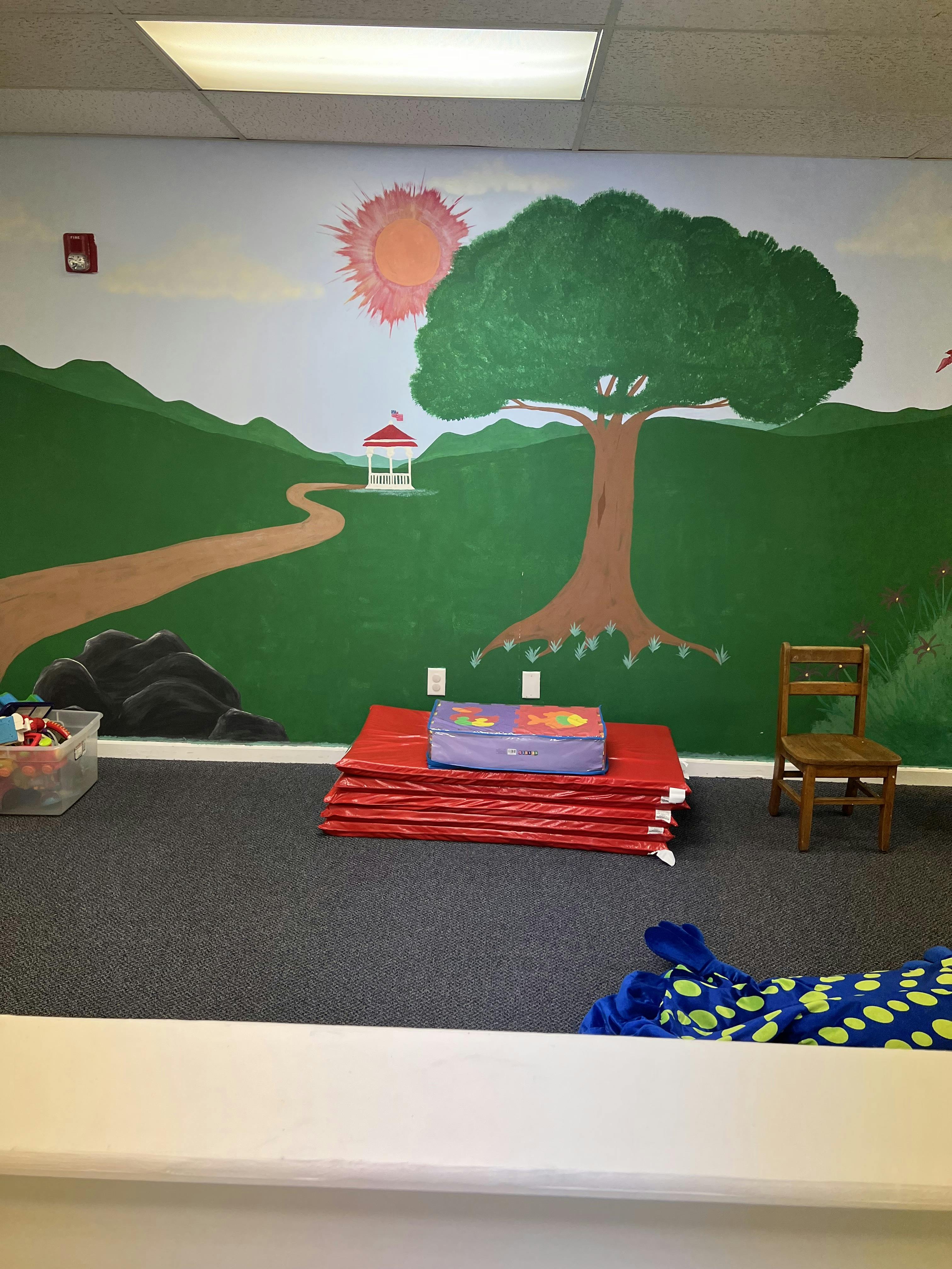 Room with mural of landscape, red mats, and a small chair