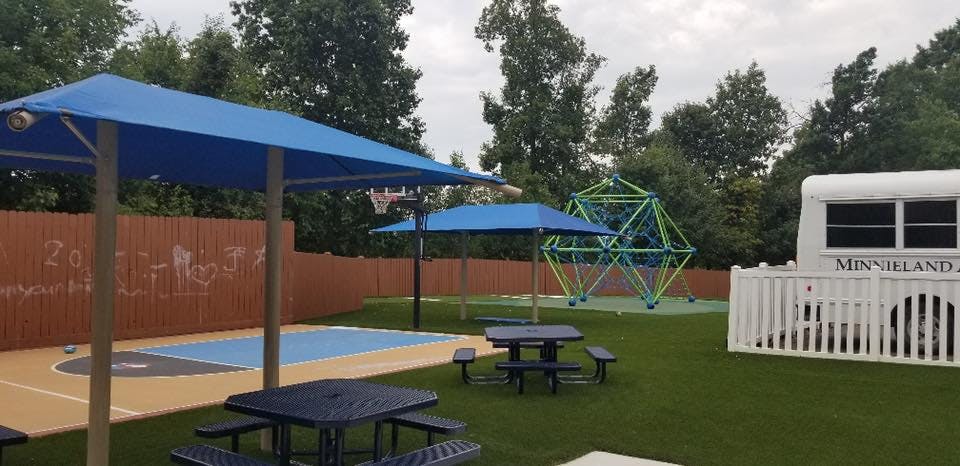 Outdoor playground with picnic tables, basketball court, and climbing dome