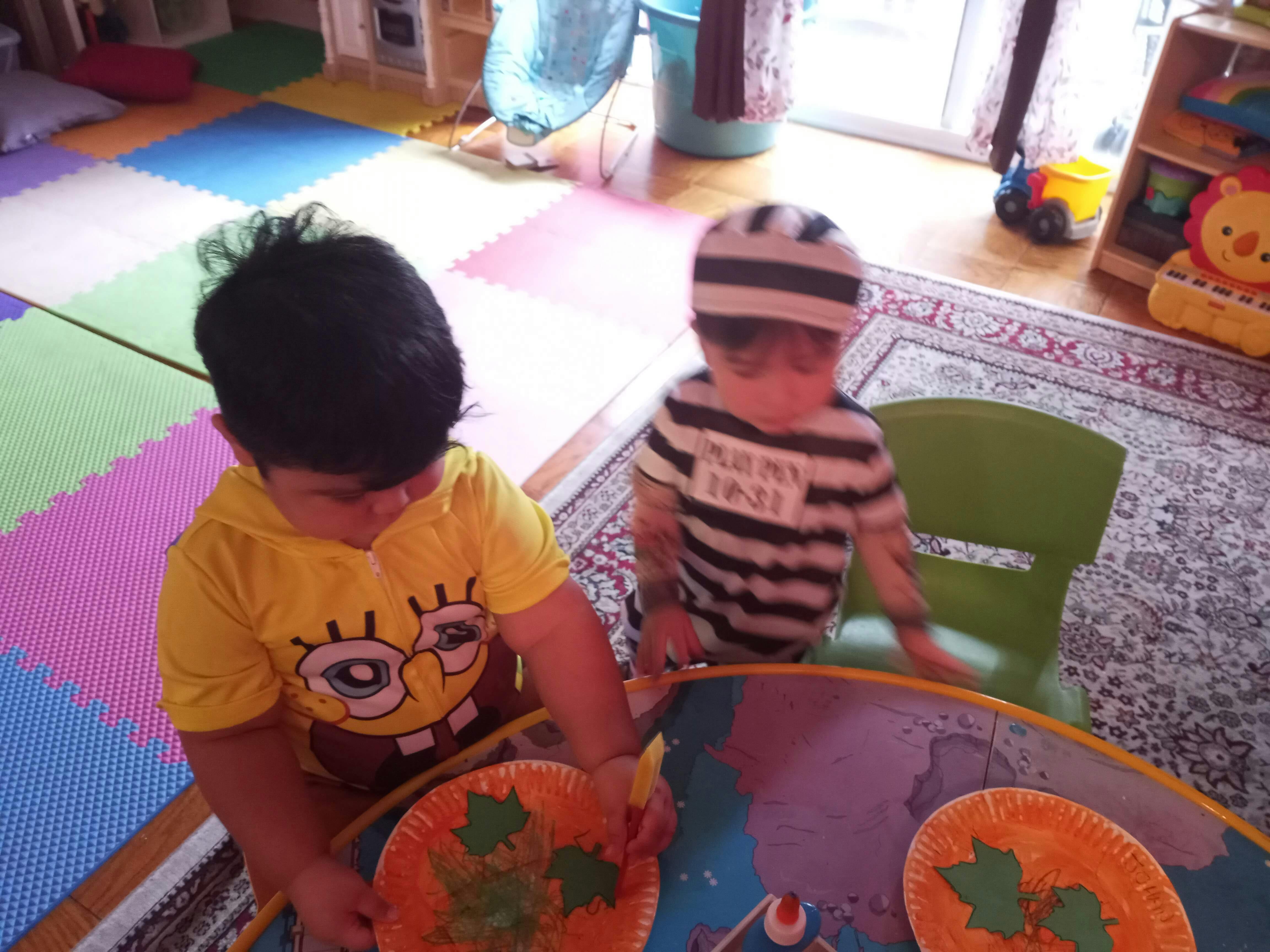 Two children playing with paper plates at a table