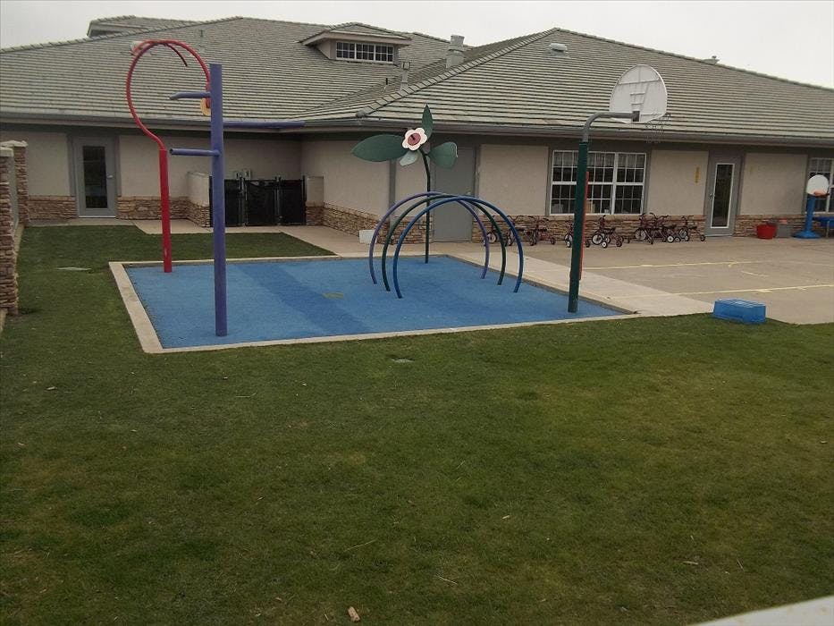 Outdoor playground with blue mat, various play structures, and small bicycles