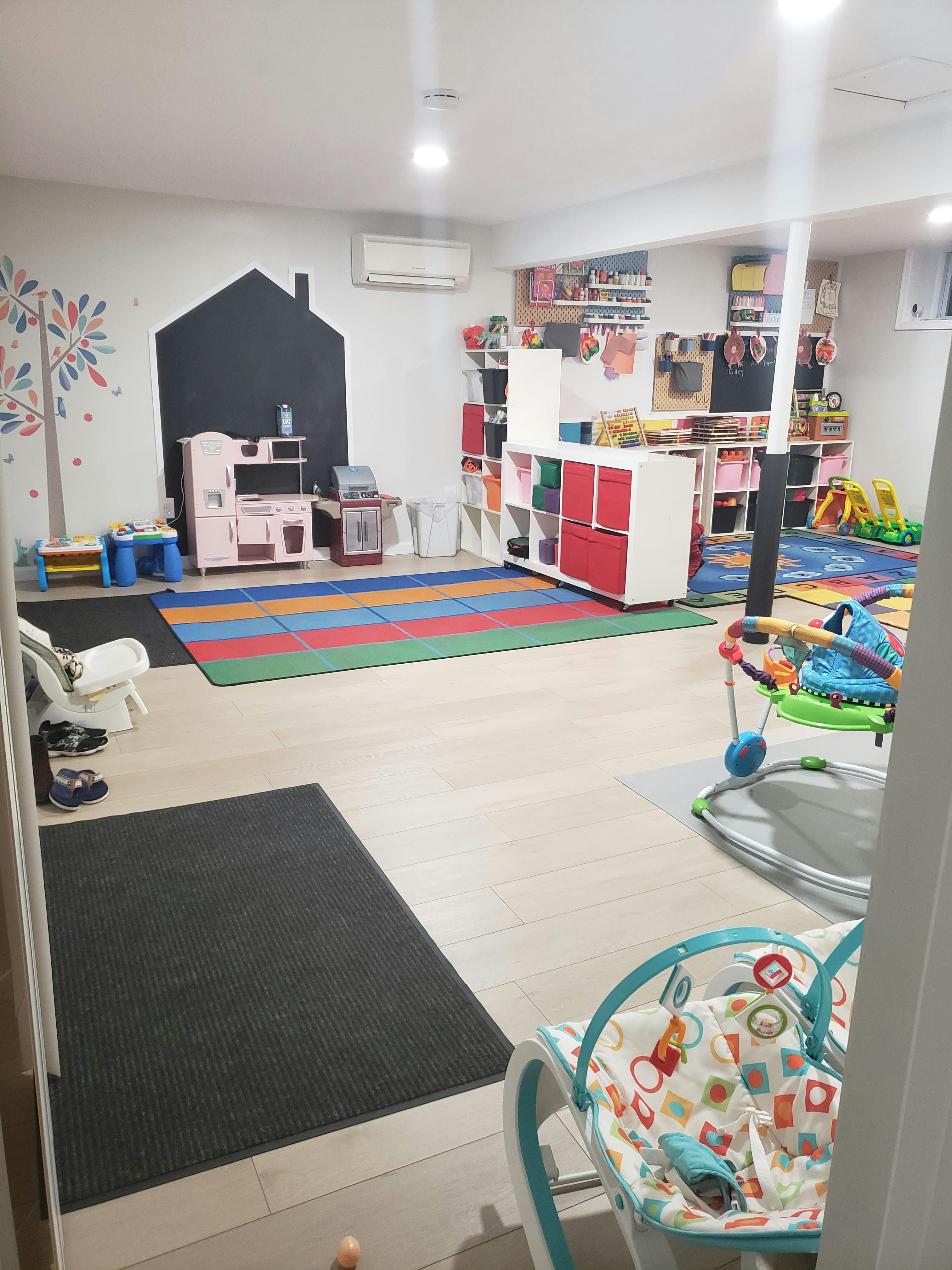 Playroom with colorful mats, toy kitchen, and shelves of shelves with toys