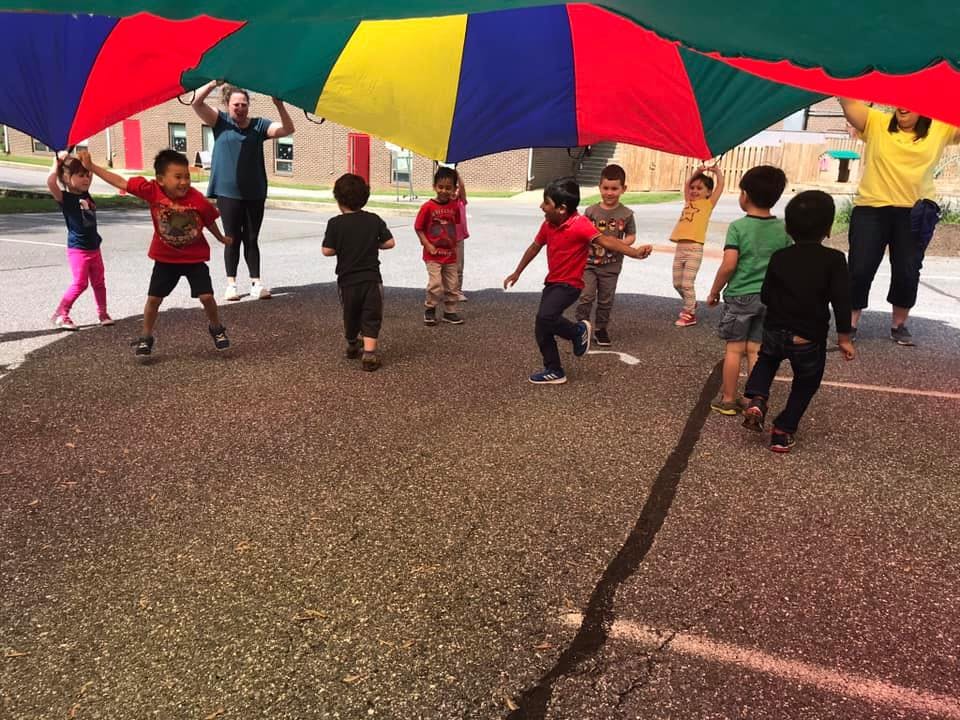 Children and adults playing with a colorful parachute outdoors
