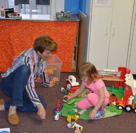 Adult and child playing with toys on the floor