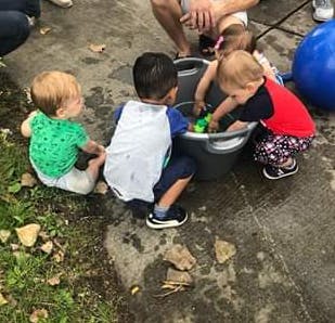 Three children playing with toys in a bucket
