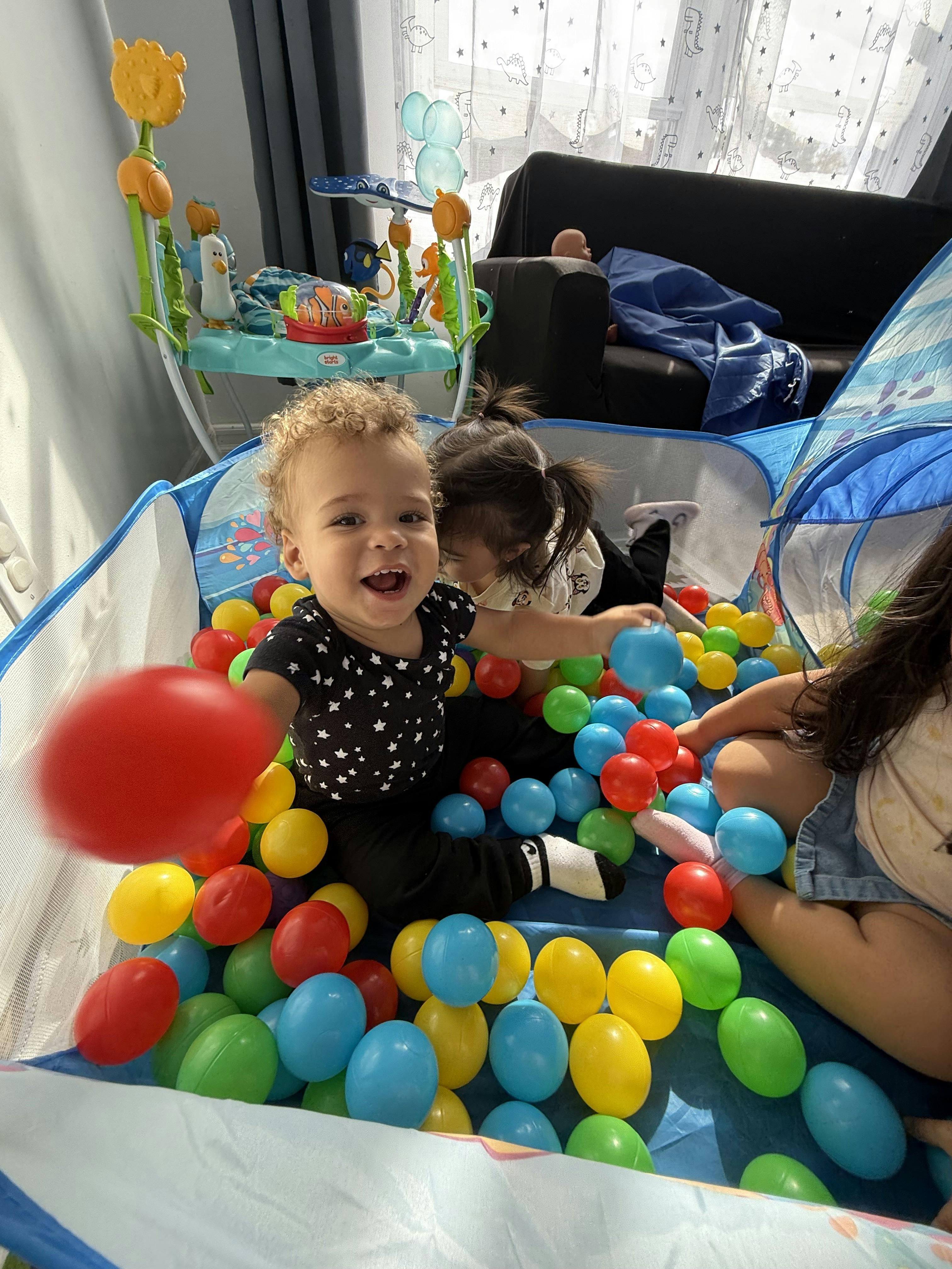 Child playing in a ball pit with another child