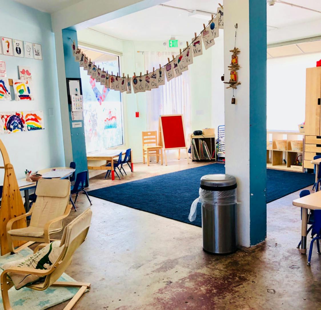 Classroom with children's artwork, small tables, and chairs