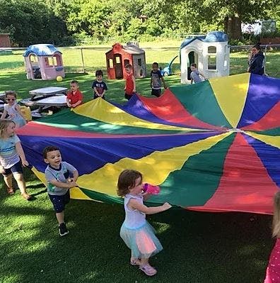 Children playing with a colorful parachute outdoors