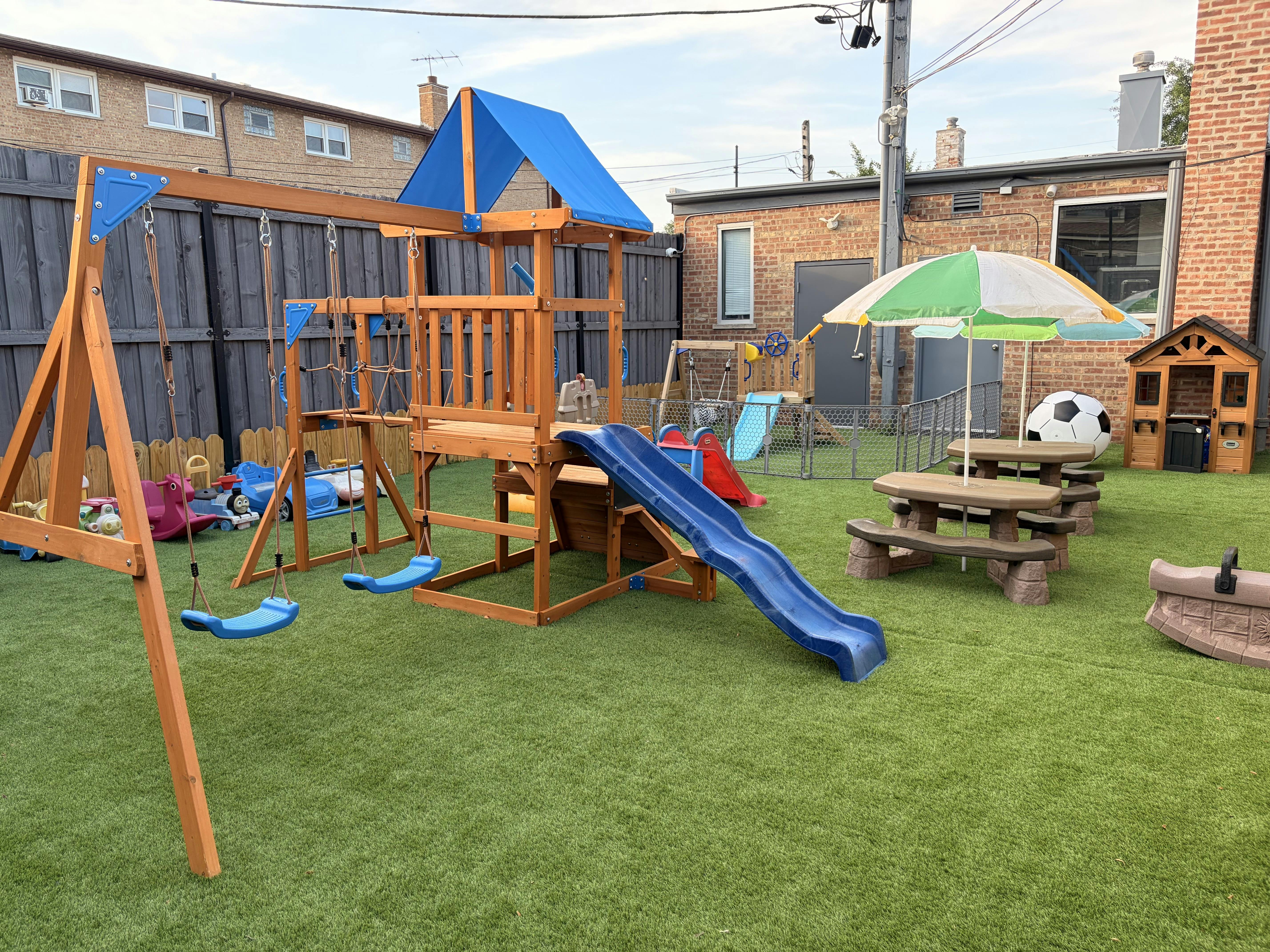 Backyard playground with a wooden play set, swings, slide, and picnic tables
