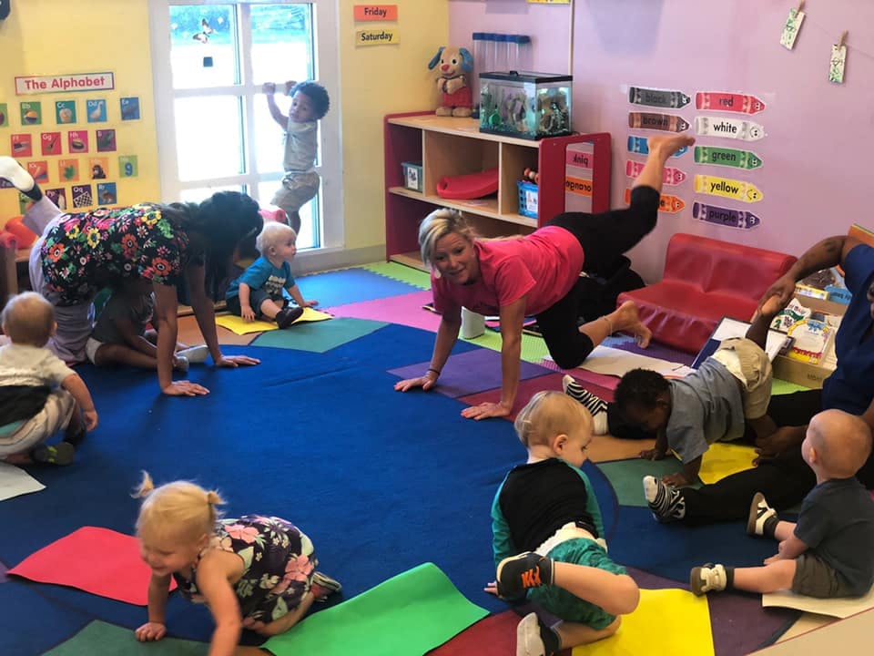 People and children doing yoga poses in a classroom