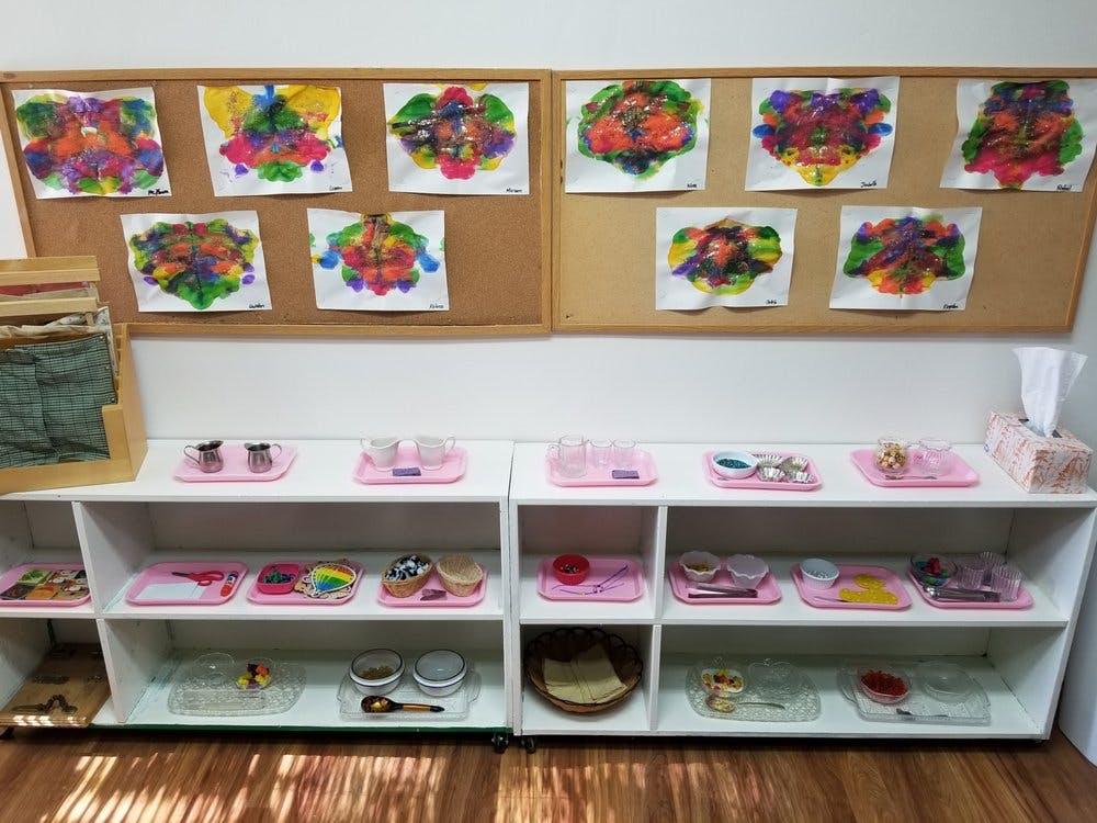 Children's artwork displayed above shelves with learning materials