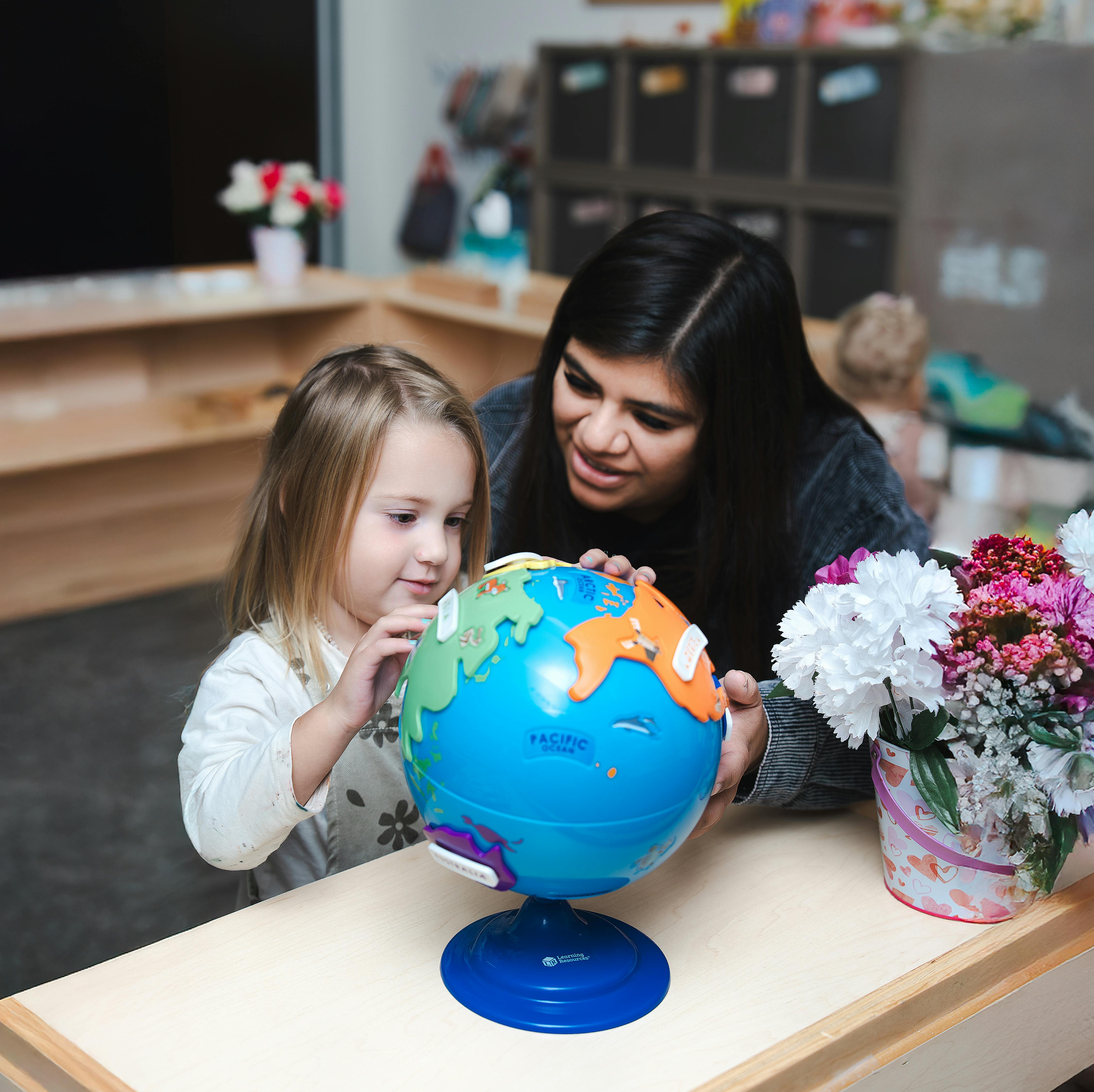 Adult and child looking at a globe in a classroom