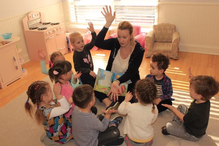 Person reading a book to a group of children in a classroom
