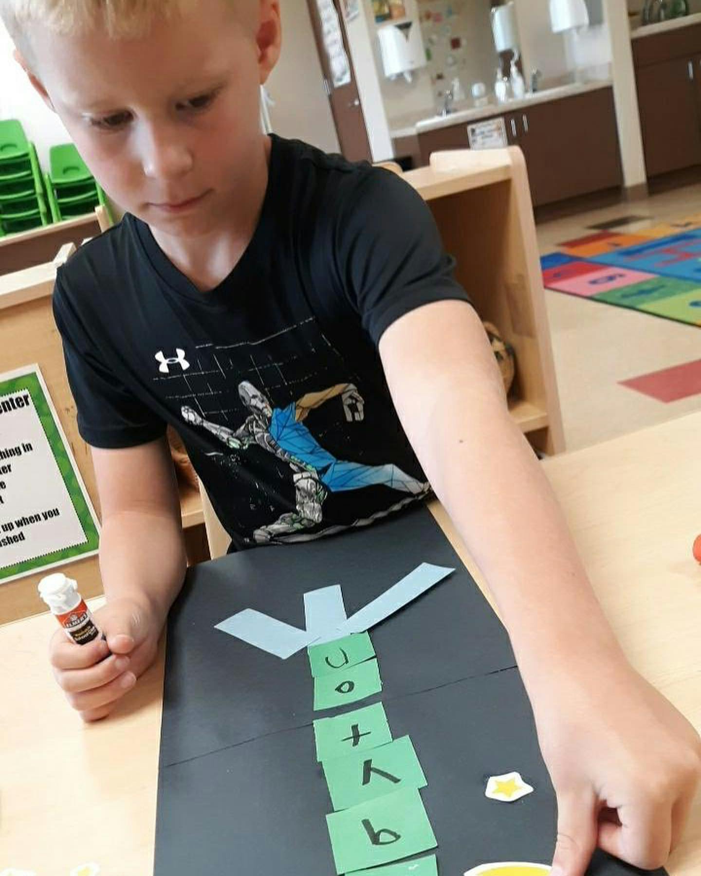 Child making a craft with paper letters and glue stick