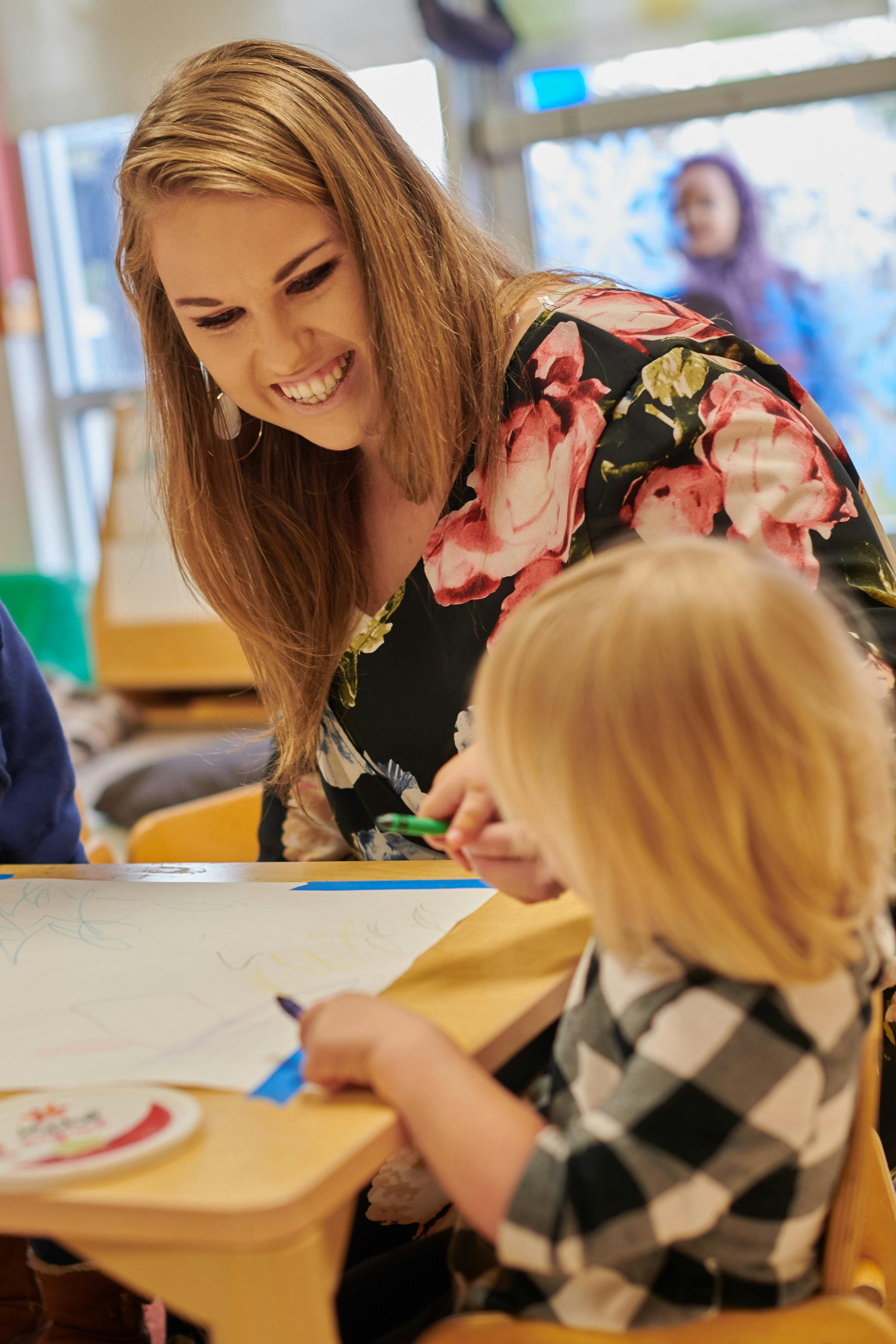Adult and child drawing at a table in a classroom