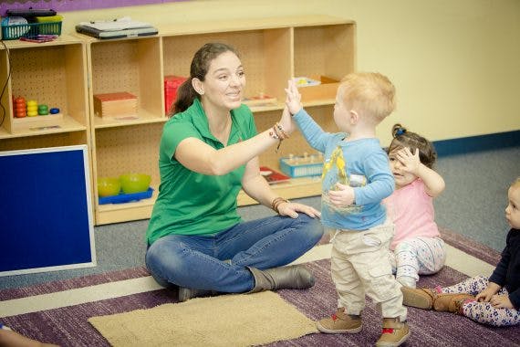Person high-fiving a child in a classroom