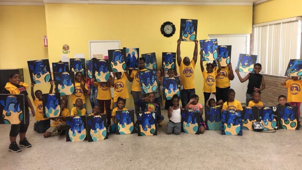 Group of people and children holding up paintings
