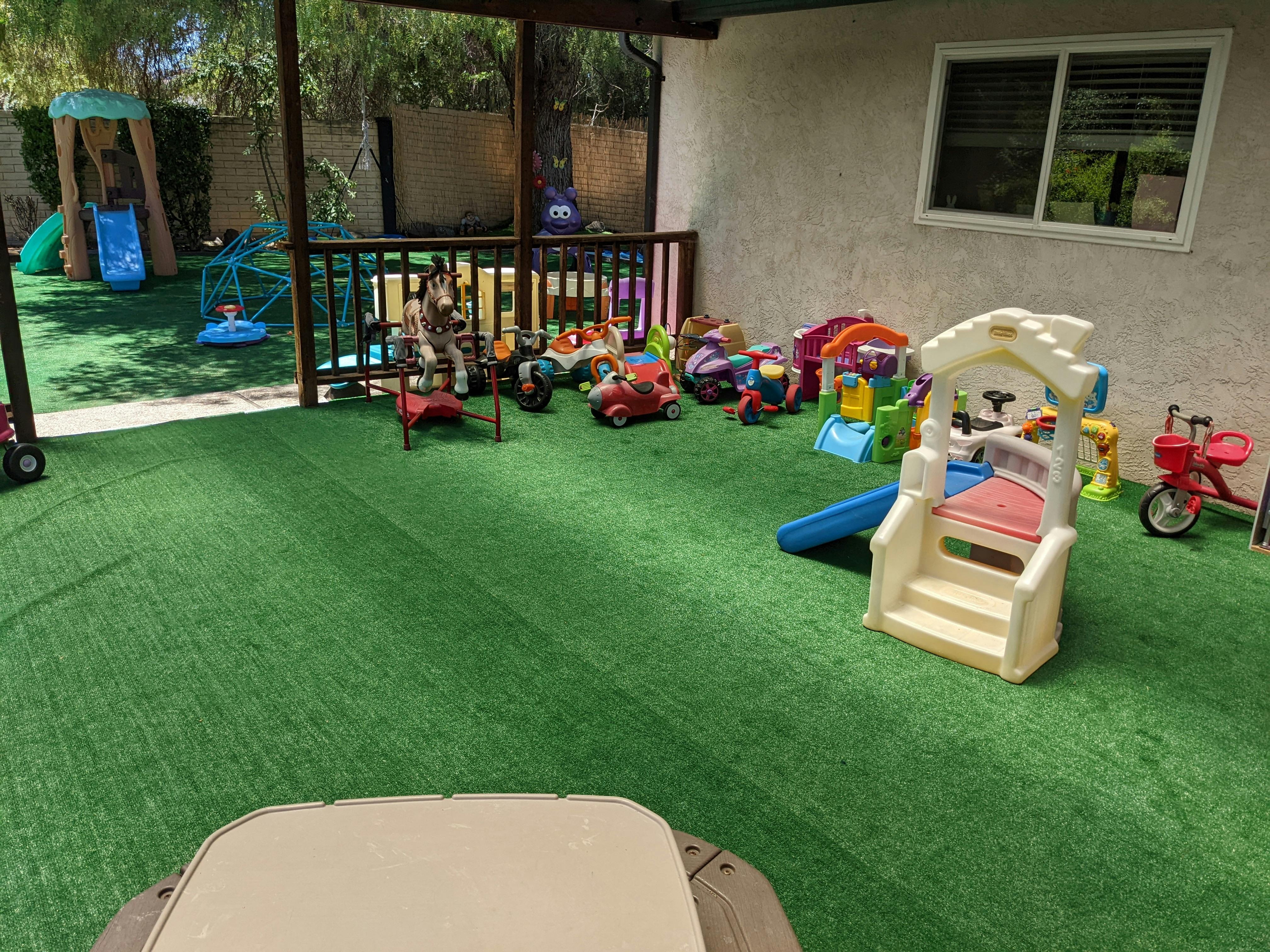 Outdoor play area with artificial turf and various children's toys and slides