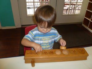Child playing with a wooden cylinder block set