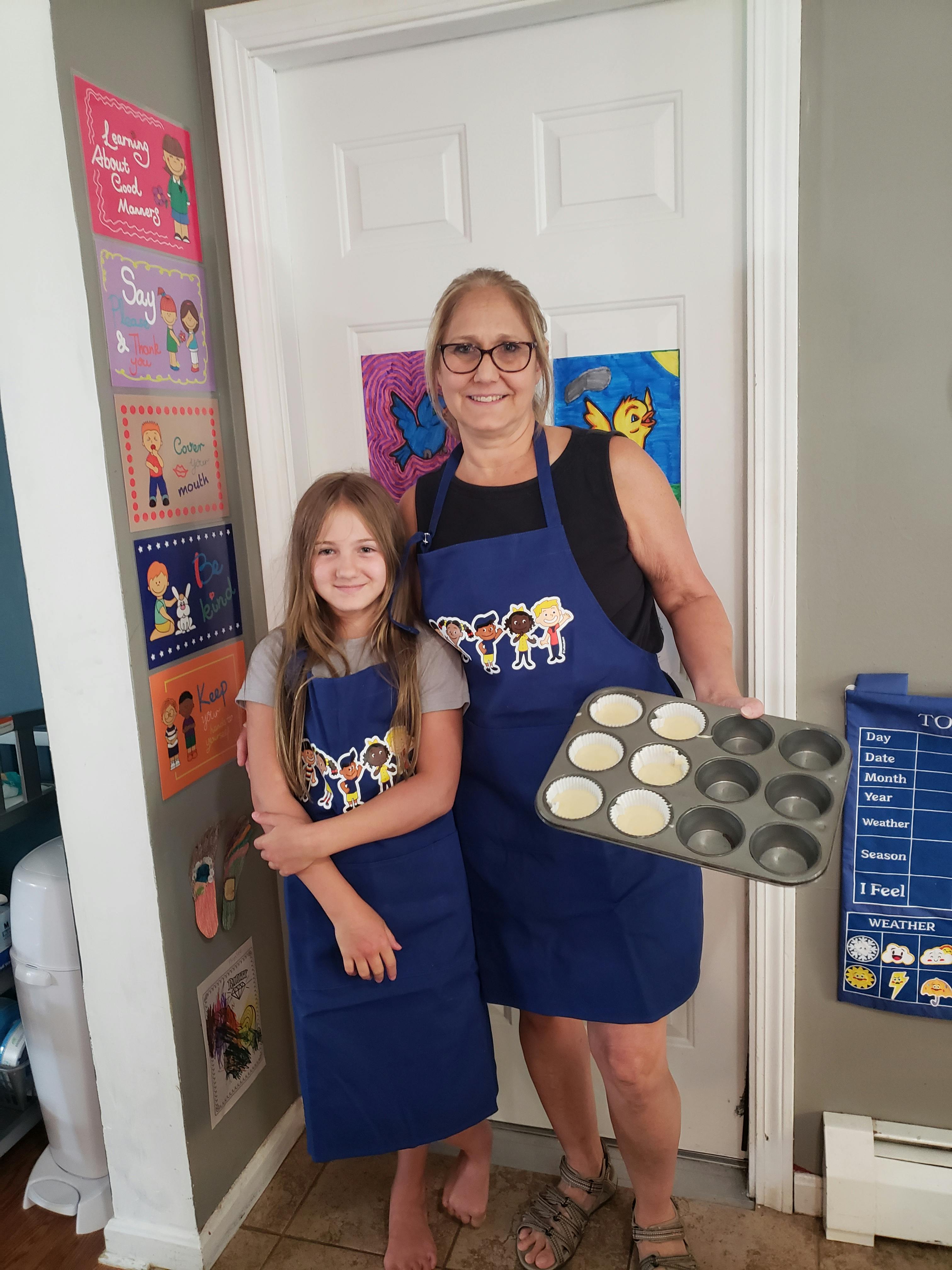 Person and child in aprons holding a muffin tin with batter