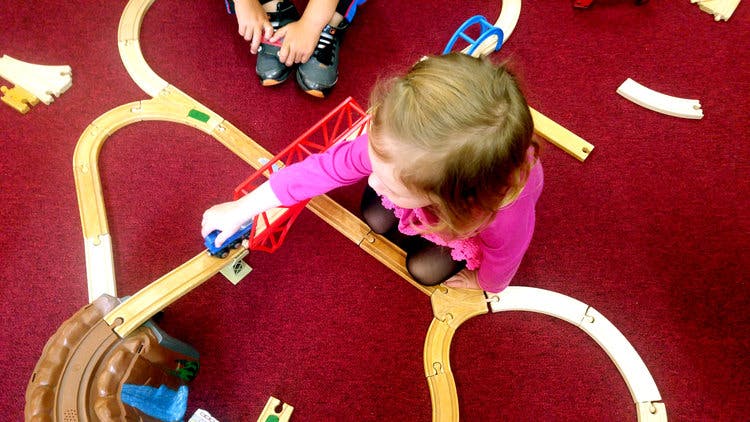 Child playing with a toy train on a wooden track