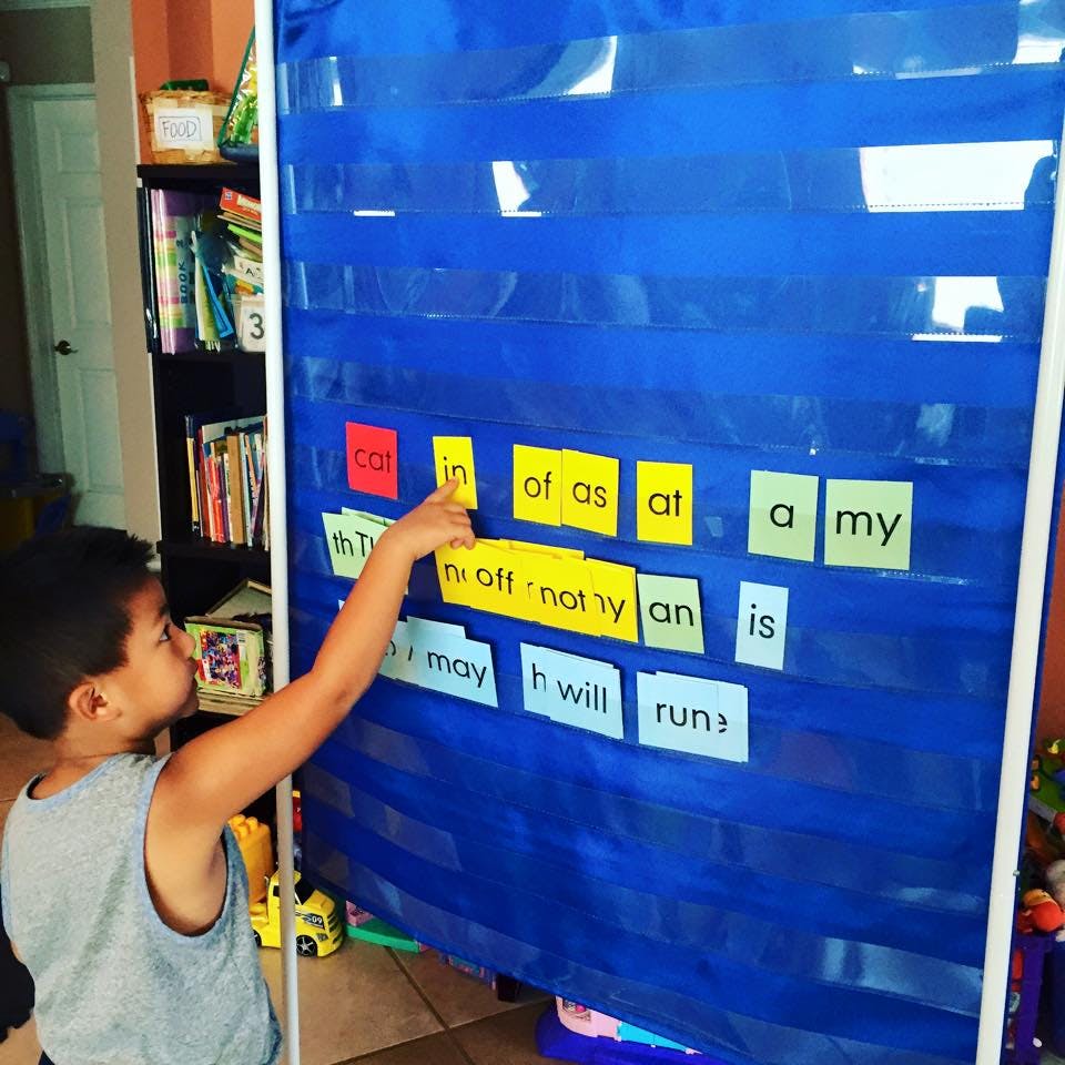Child pointing at words on a blue pocket chart