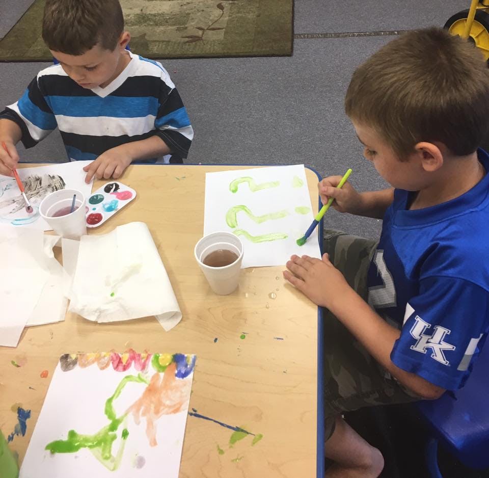 Two children painting at a table