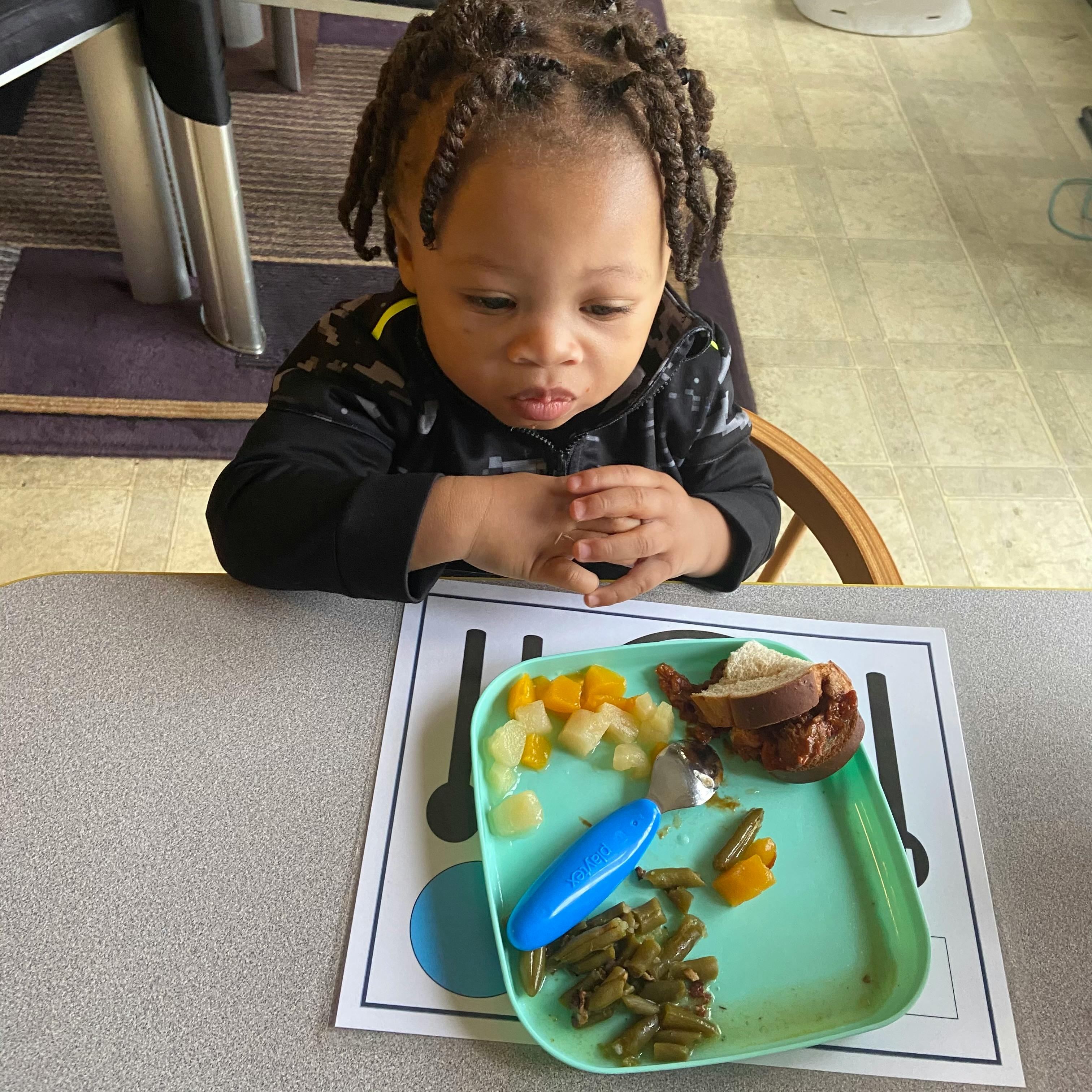 Child looking at a plate of food on a table