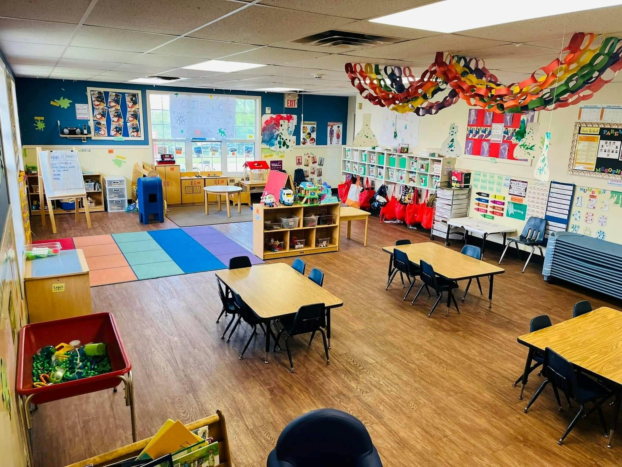 Empty classroom with small tables and chairs, colorful decorations, and a science lab sign