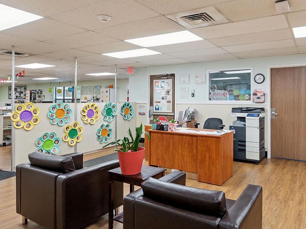 Lobby area with a reception desk, sofa, and flower decorations with child faces