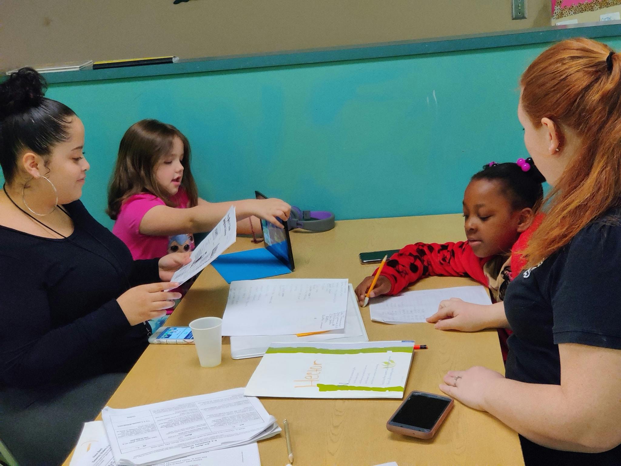 Four people at a table with papers and a tablet
