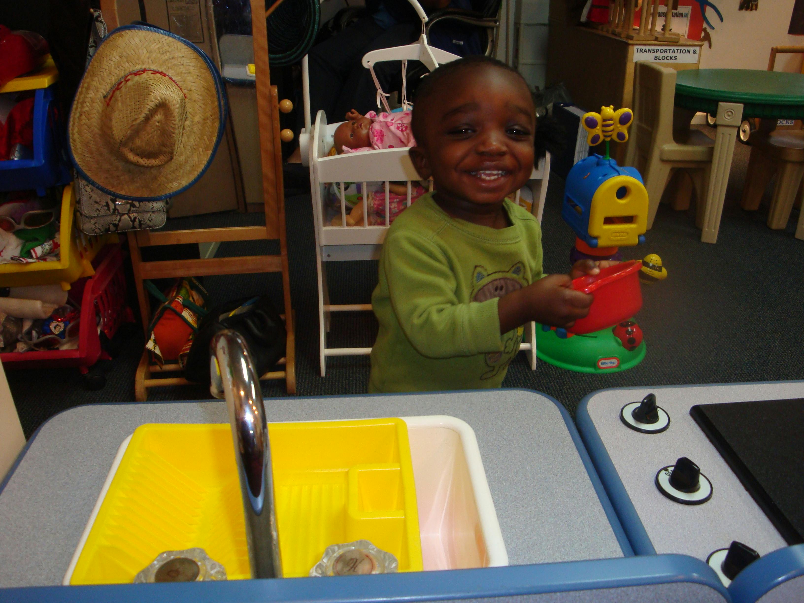 Child holding a colorful toy in a play kitchen