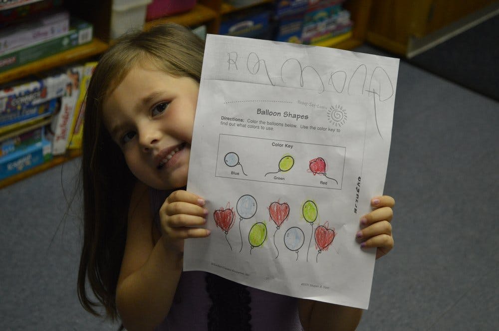 Child holding up a drawing of balloons