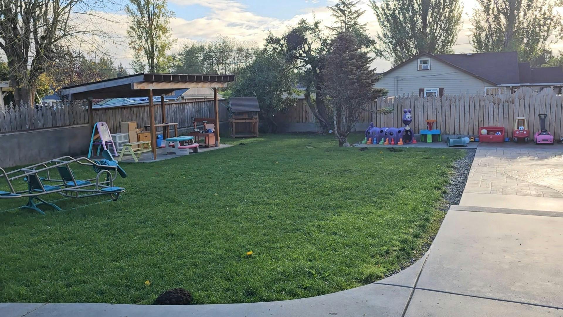Grassy backyard with play equipment and a covered patio