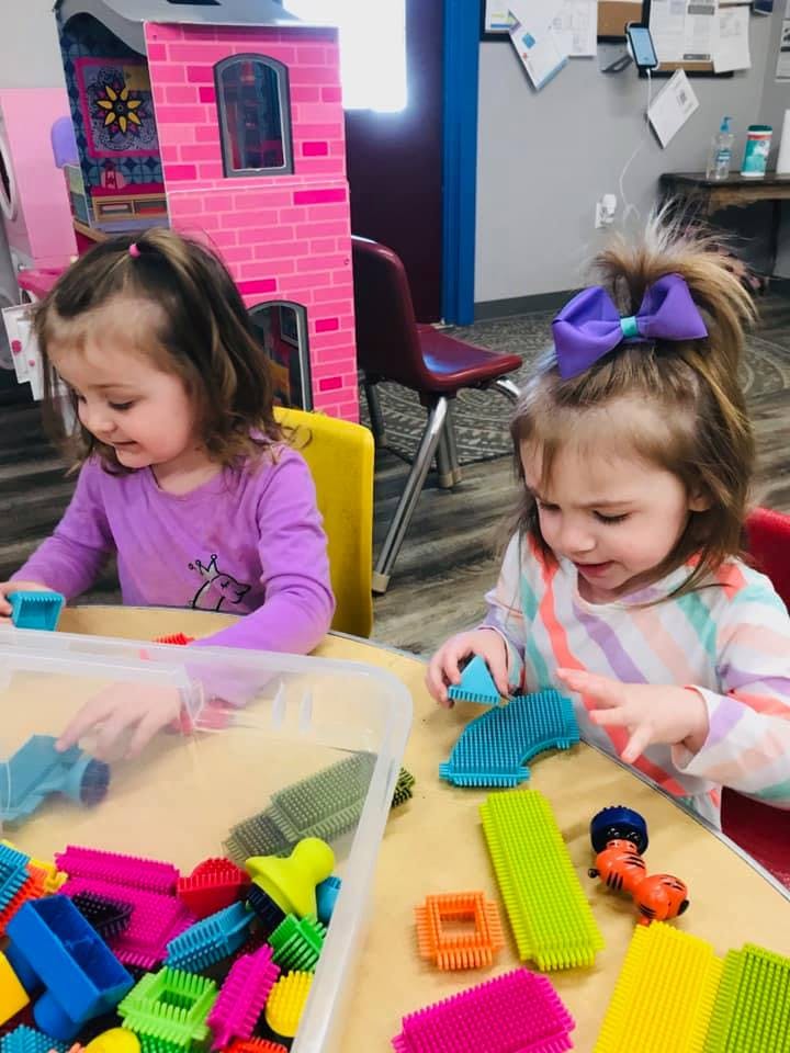 Two children playing with colorful building blocks at a table
