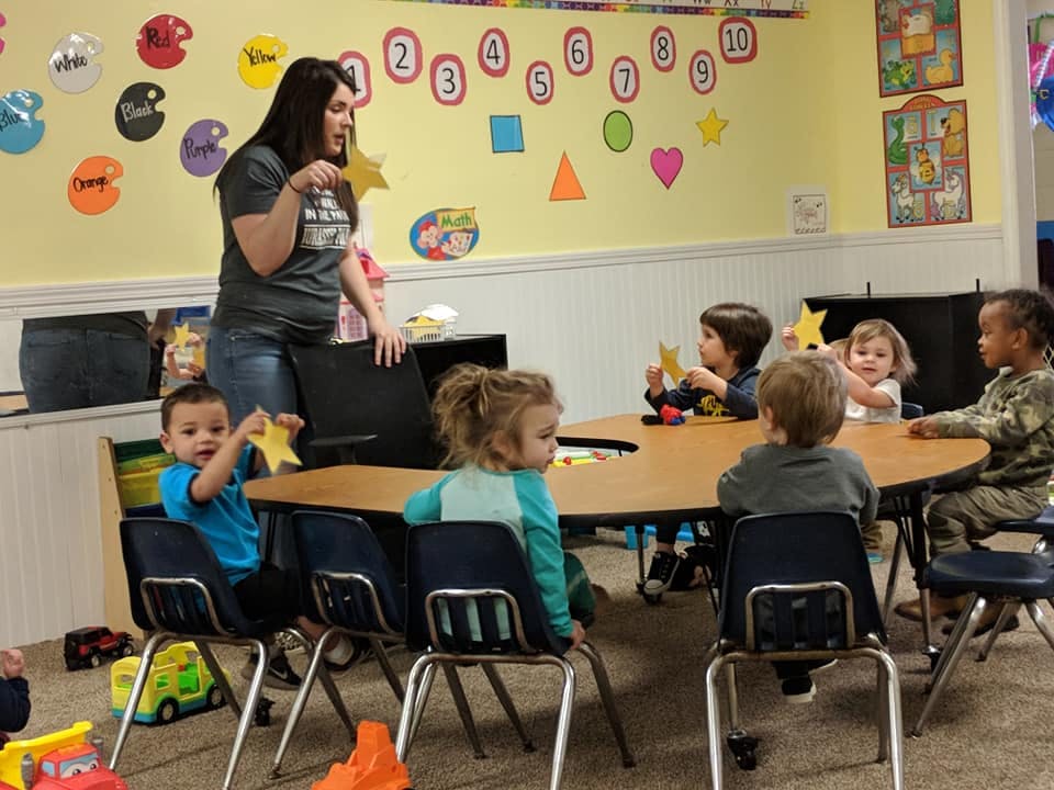Adult and children sitting at a table in a classroom