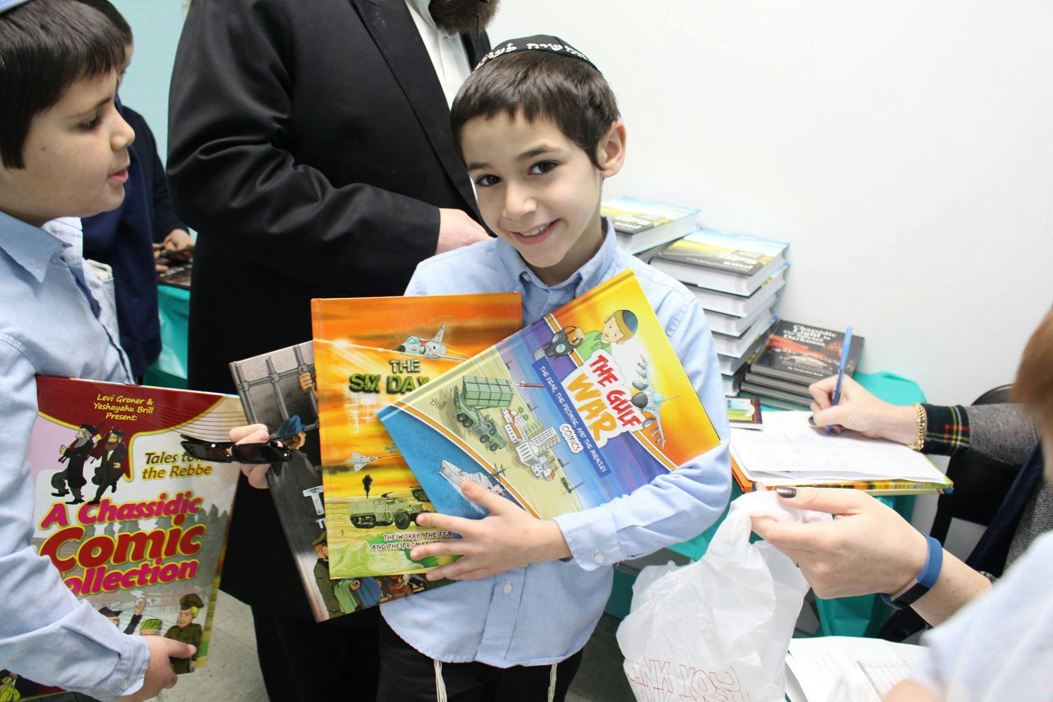 Child holding several books, one titled "The Guf War"
