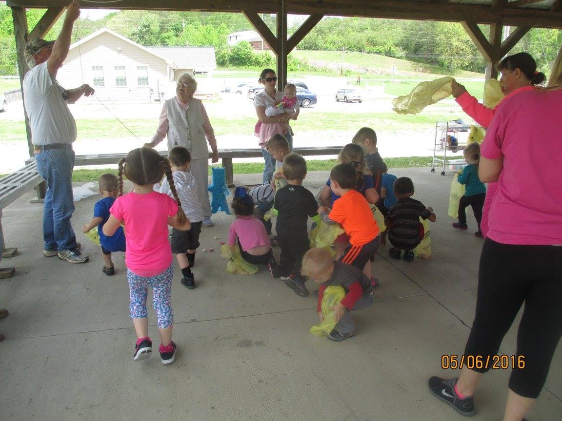 Adults and children gathered under a shelter