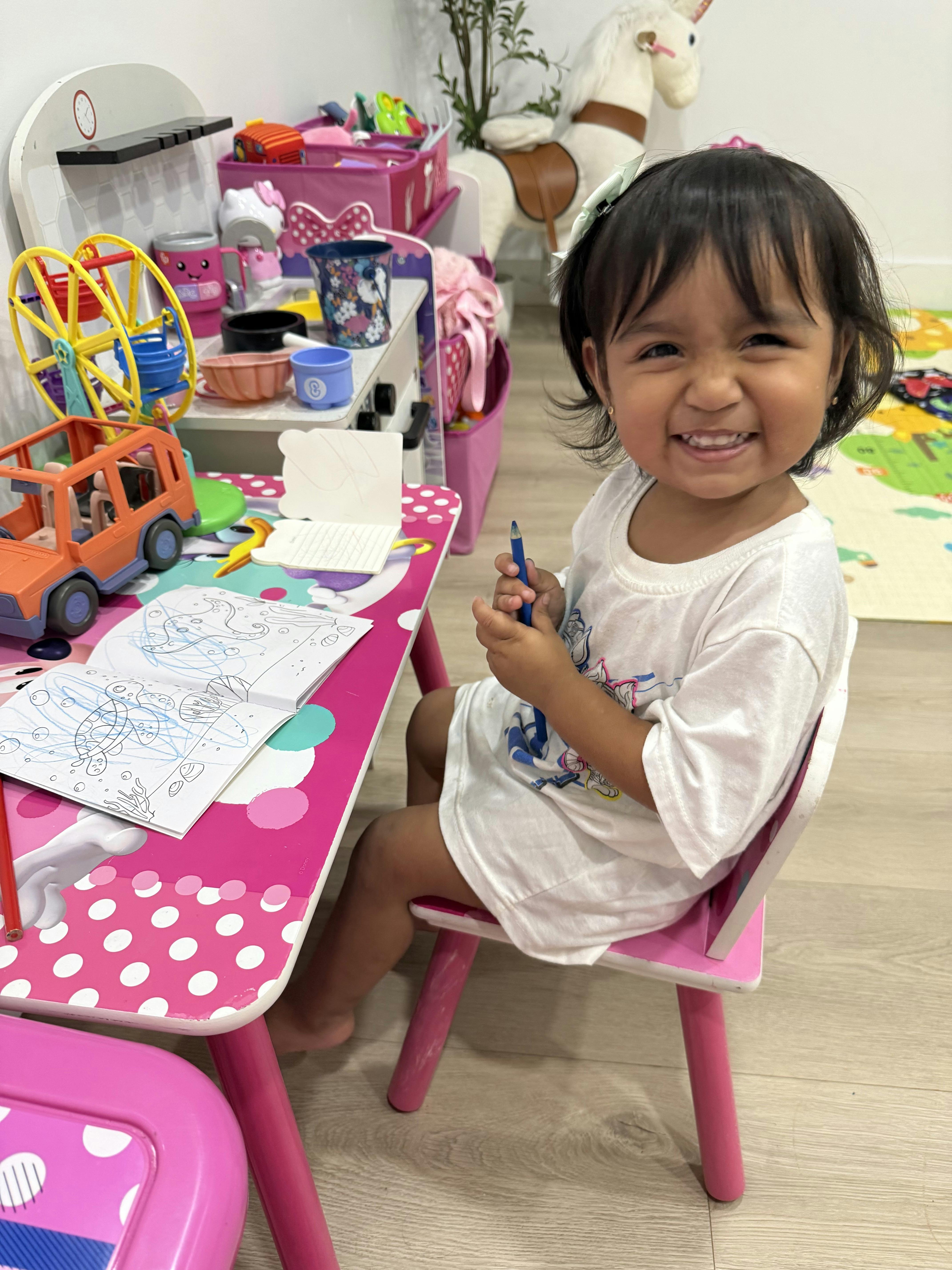 Child sitting at a small play table coloring in a book