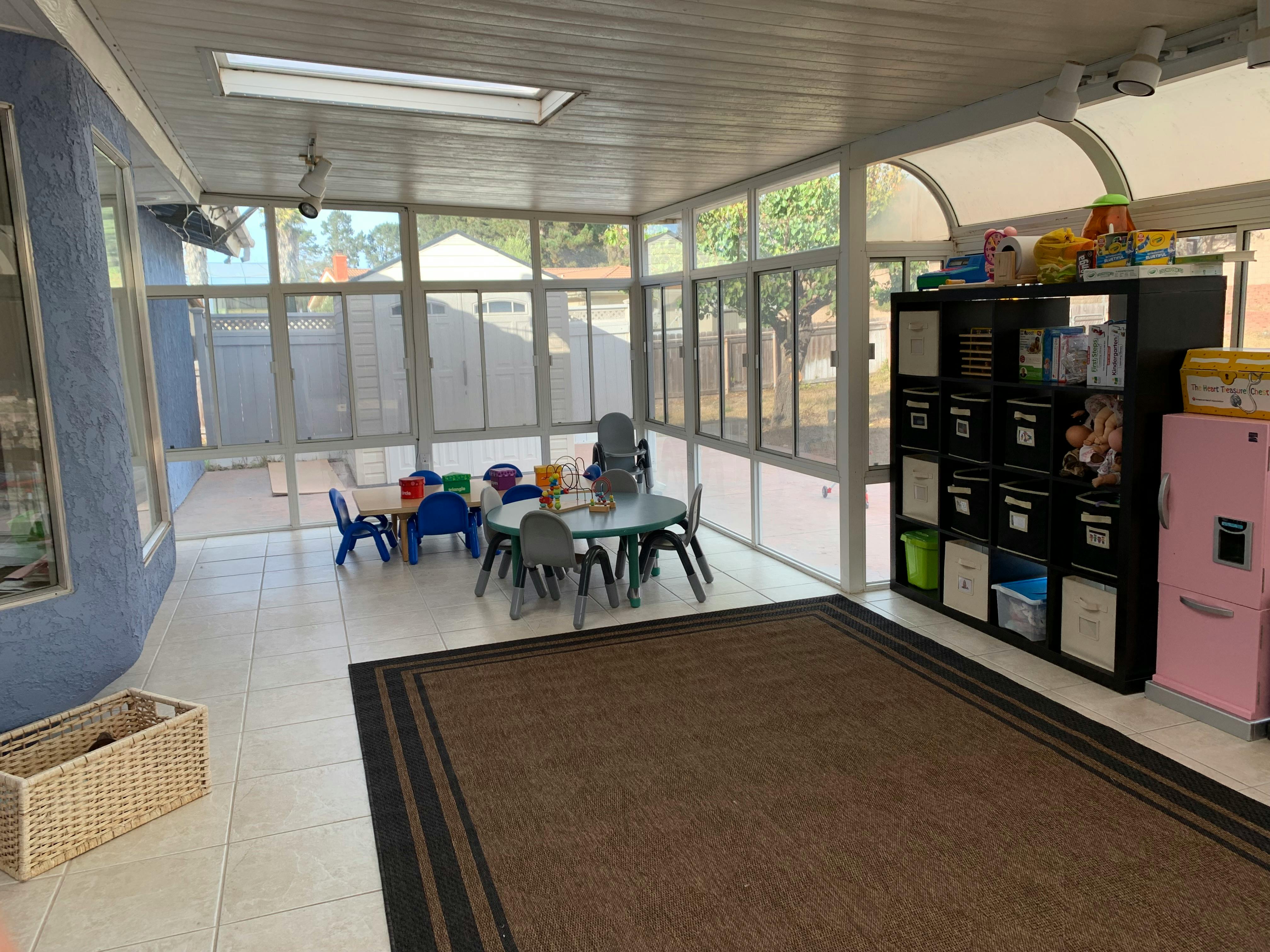 Sunroom with small table and chairs, storage unit, and pink refrigerator