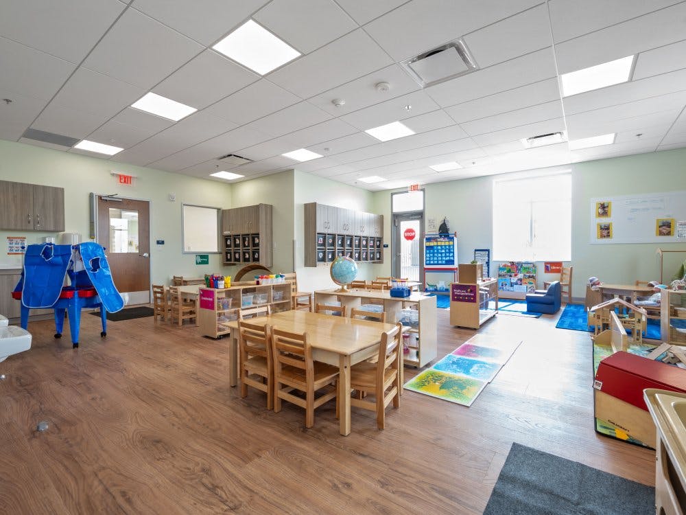 Empty classroom with small wooden tables and chairs, and play areas