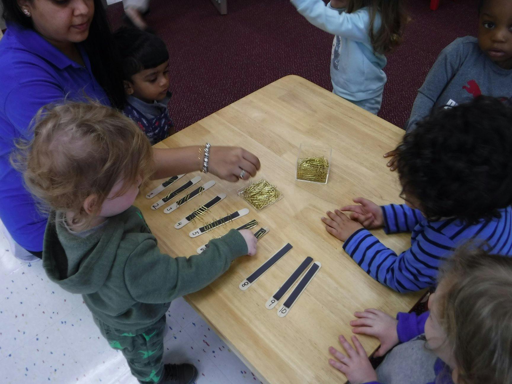 Person and children at a table with learning materials