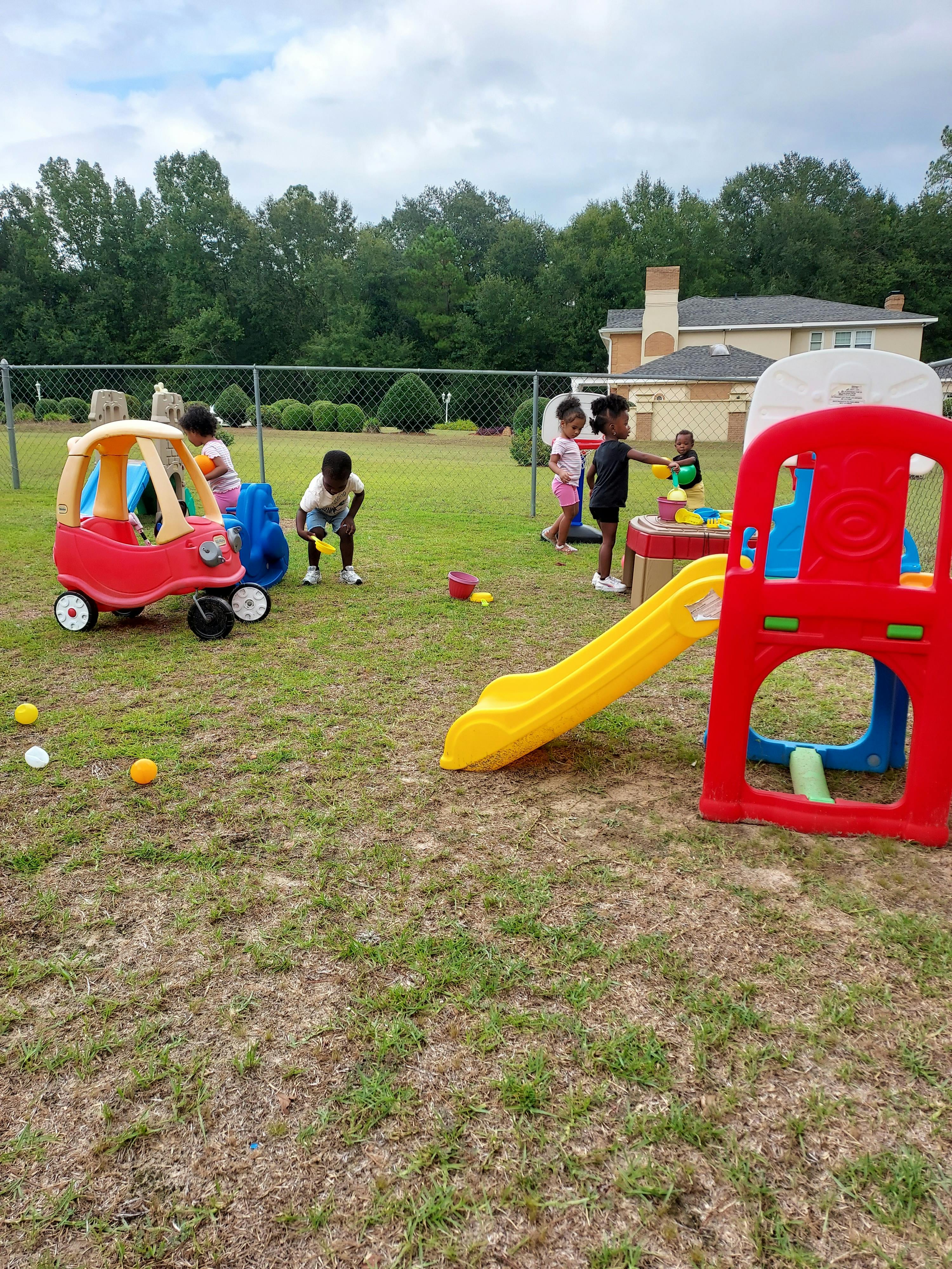 Children playing on a playground with a slide and toy car