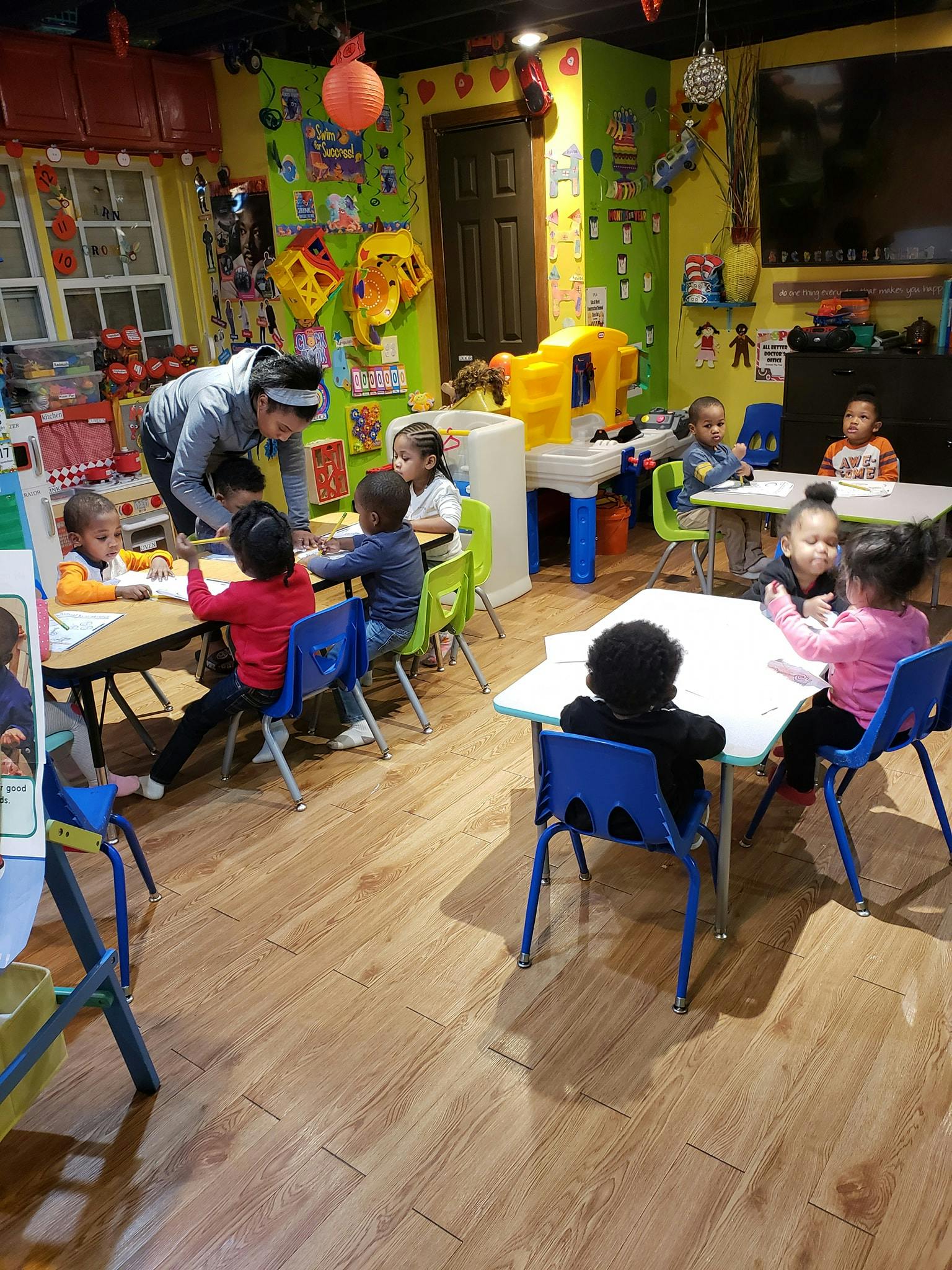 Adult supervising children at tables in a classroom