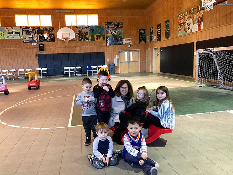 Adult and multiple children posing in a gymnasium