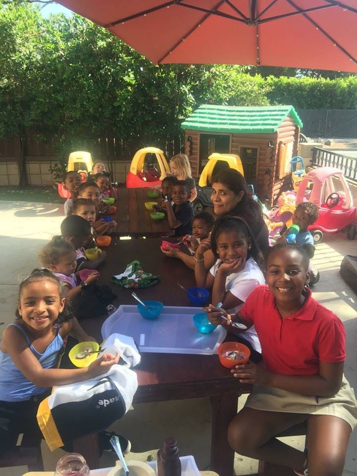 Adult and children sitting at a table outdoors with bowls